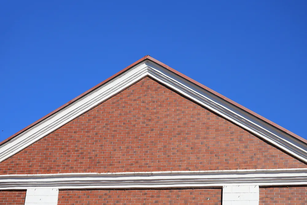 Brick commercial building with fresh white roofline trim standing against a clear blue sky